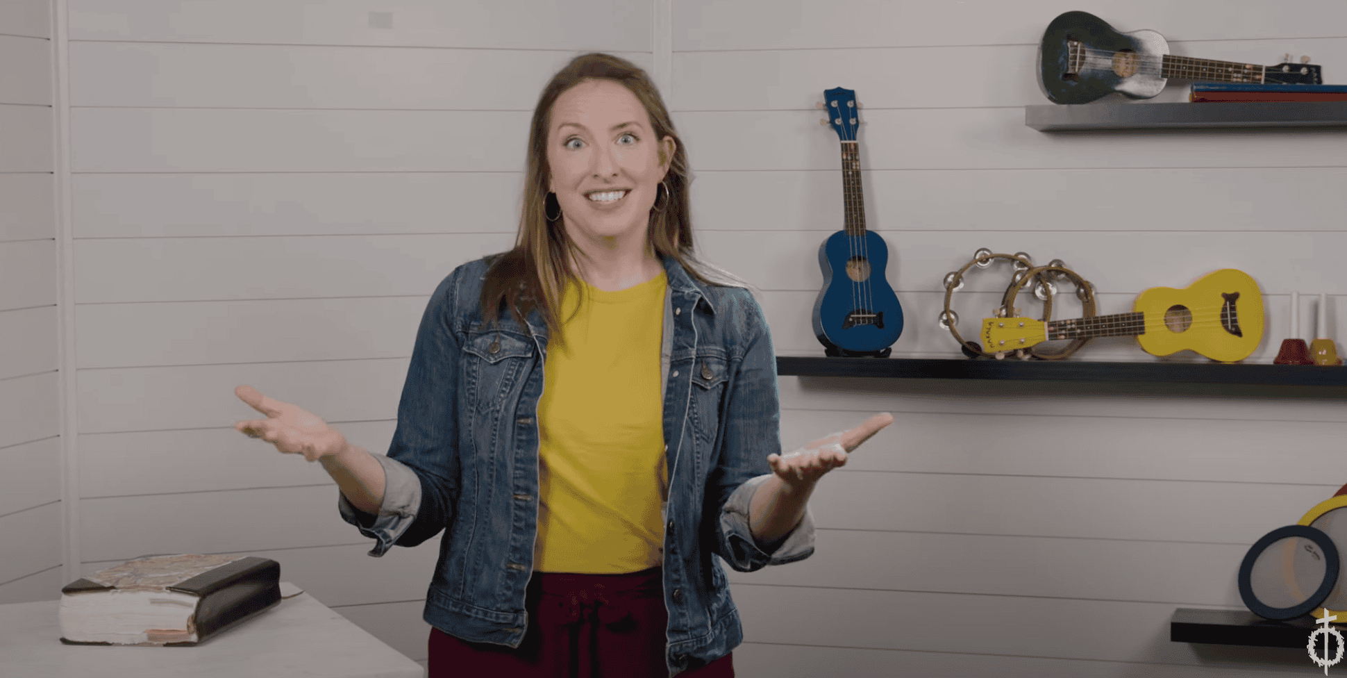 Worship leader speaking in a studio with musical instruments on the wall.